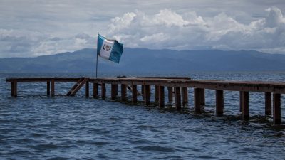 a wooden pier with a flag of guatemala on a body of water