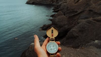 man with tattoos holding a compass at a rocky seashore in crimea ukraine