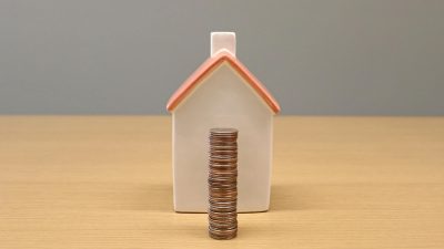 stack of coins in front of a porcelain house