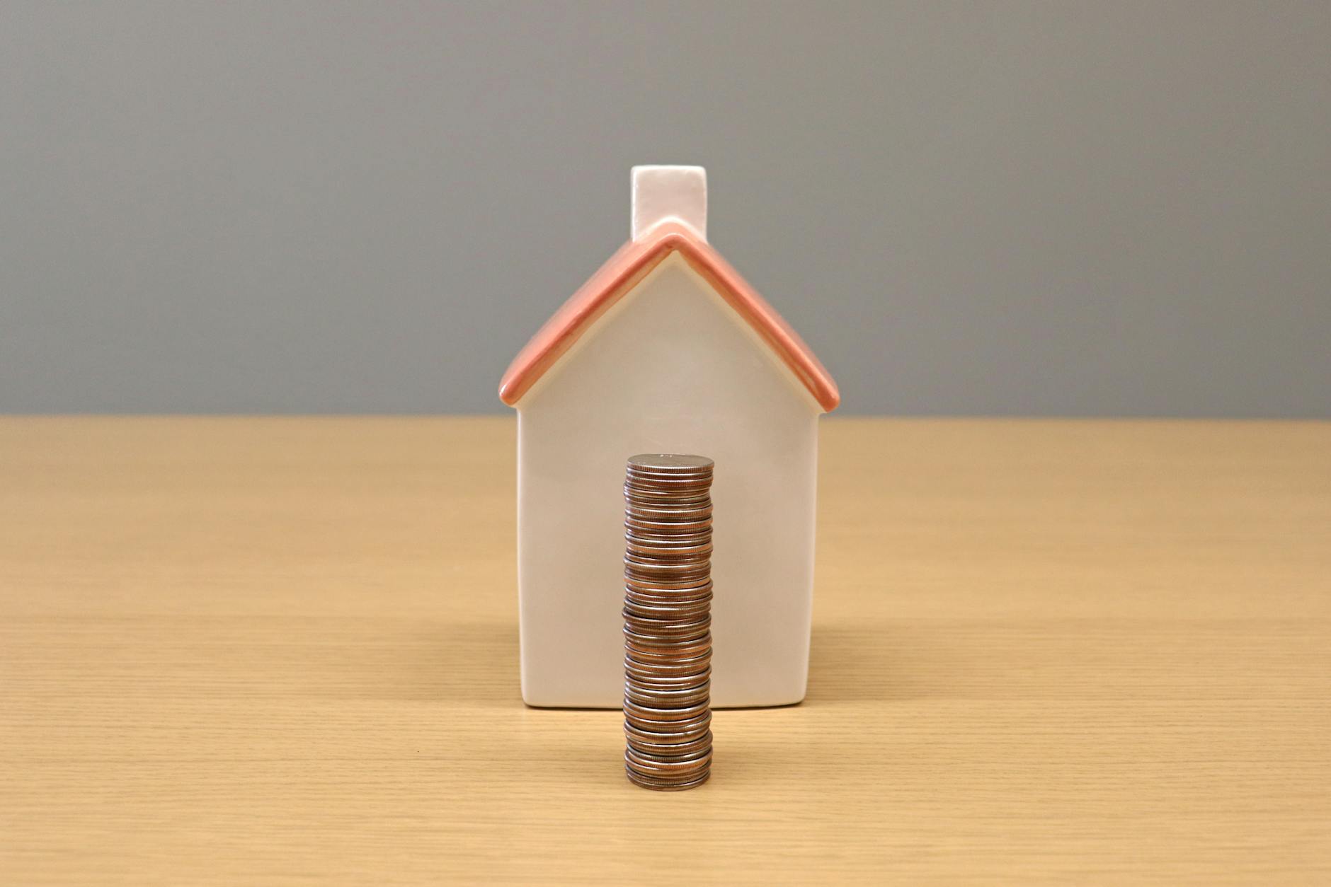 stack of coins in front of a porcelain house