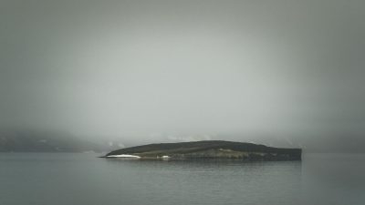 view of an island on a body of water under a gray cloudy sky