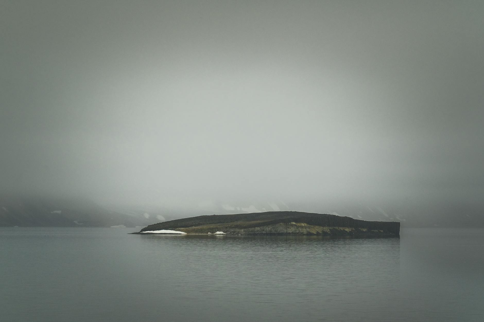 view of an island on a body of water under a gray cloudy sky