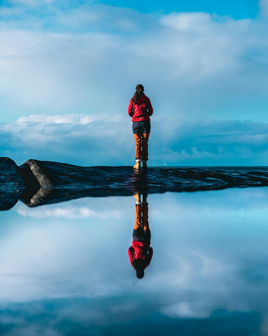 woman standing on rock near body of water