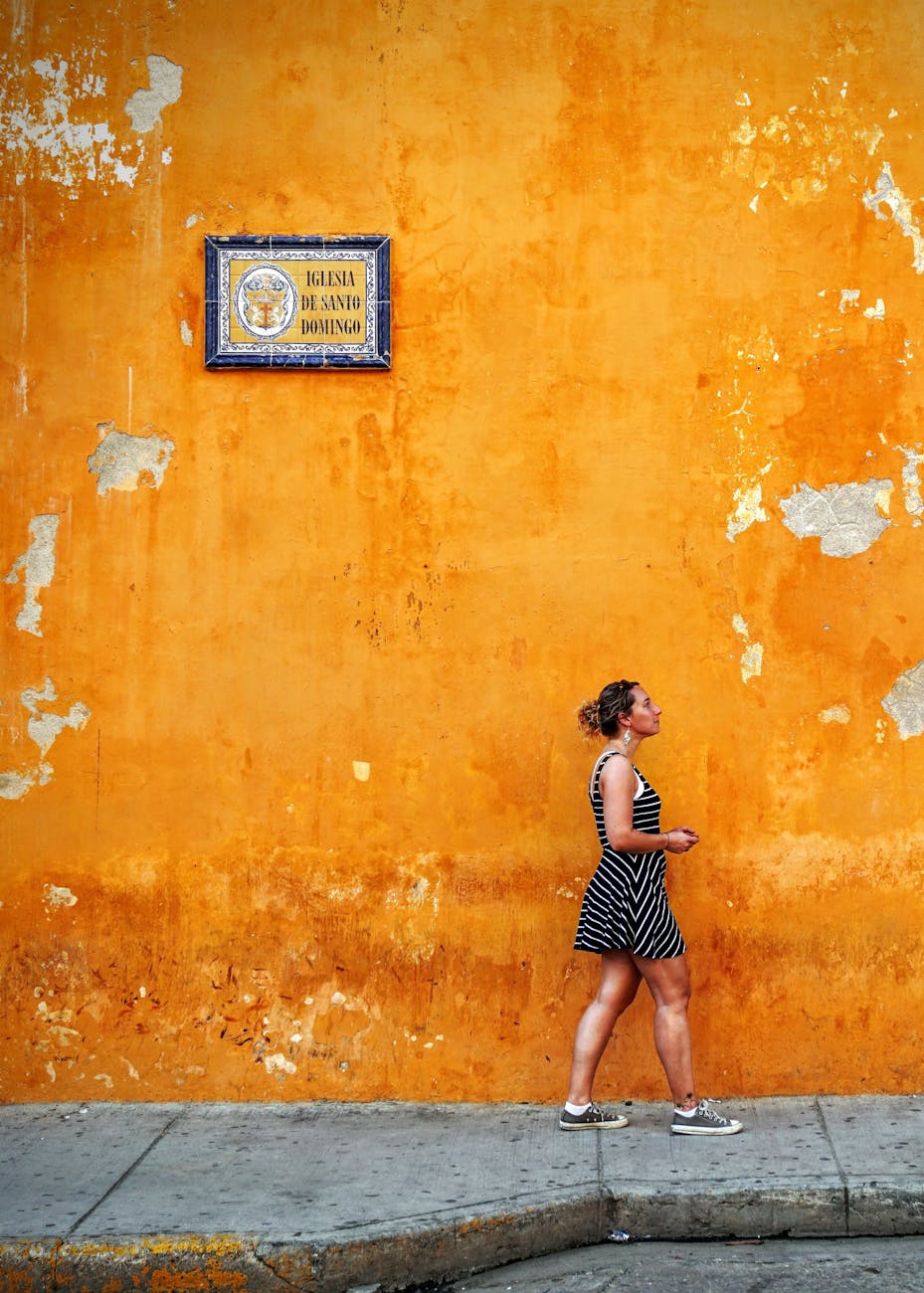 woman standing beside orange wall