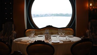 a set table by the round window in a restaurant on a cruise ship