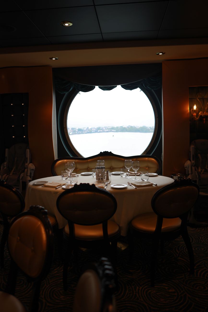 a set table by the round window in a restaurant on a cruise ship