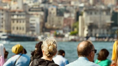 people sitting on sea shore with galata tower behind in istanbul