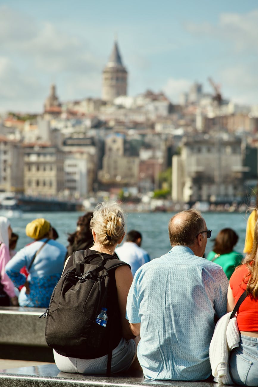 people sitting on sea shore with galata tower behind in istanbul