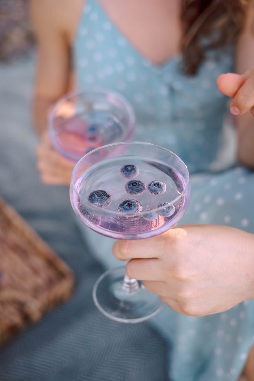 a woman holding a glass of wine with blueberries