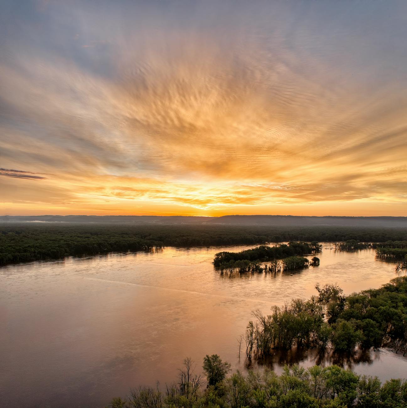 a sunset over a river with trees and water