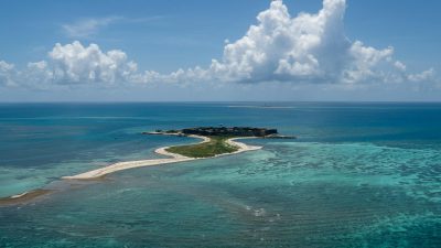 an island surrounded by blue water and white sand