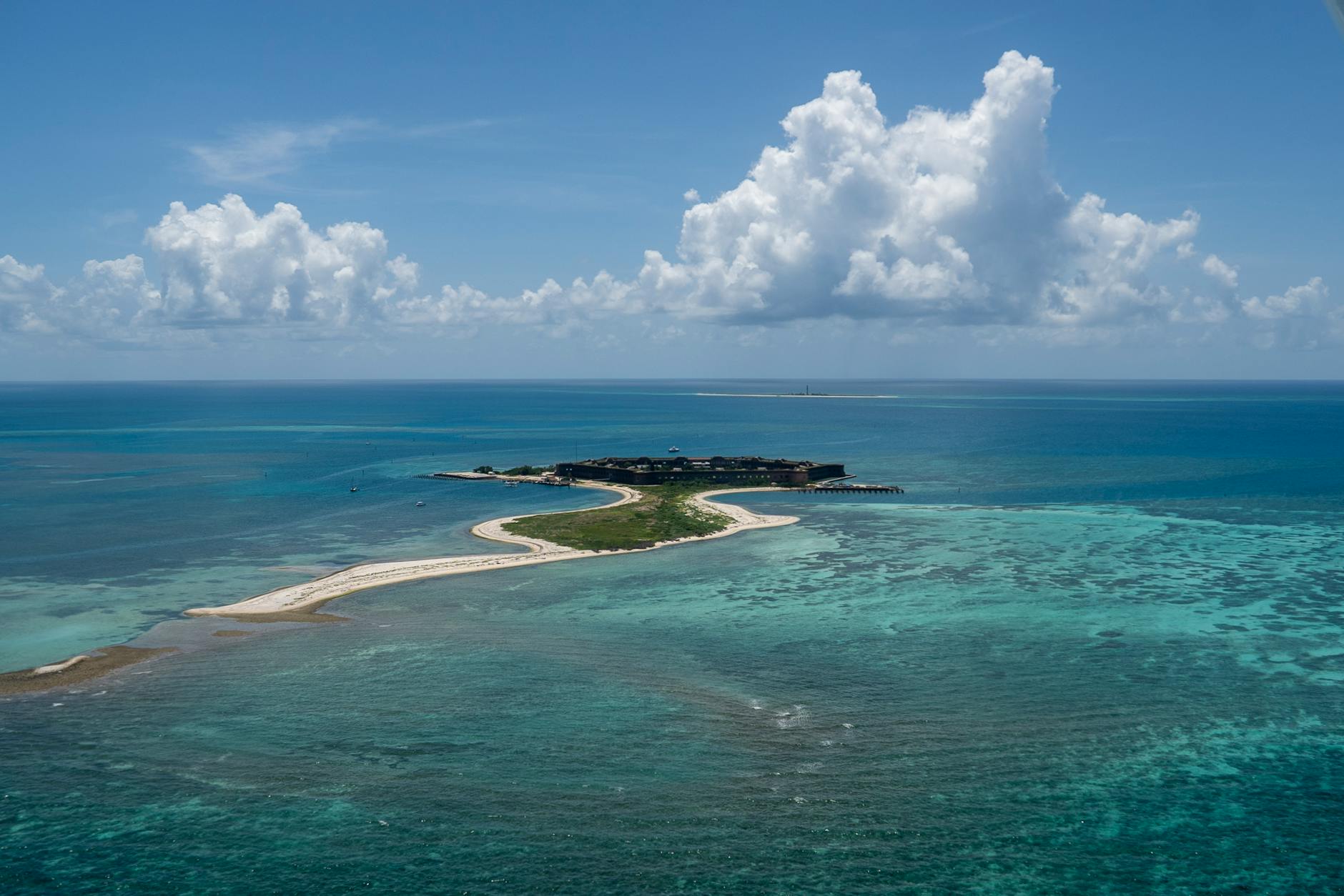an island surrounded by blue water and white sand