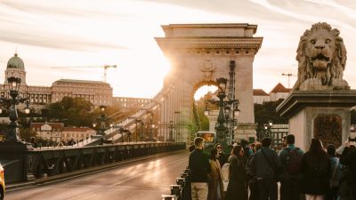 tourists on szechenyi chain bridge at sunset
