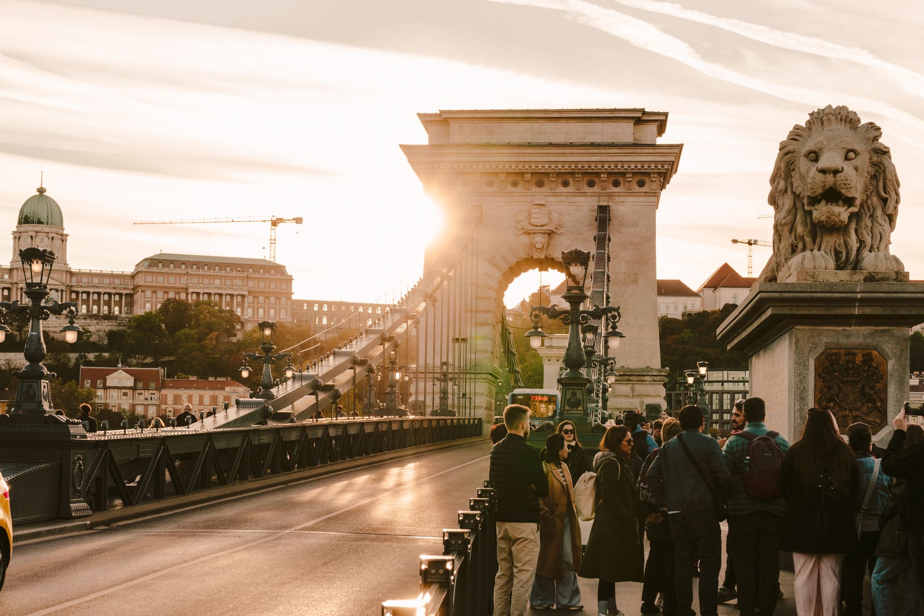 tourists on szechenyi chain bridge at sunset