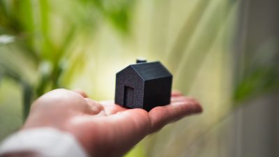 miniature house model in open hand outdoors
