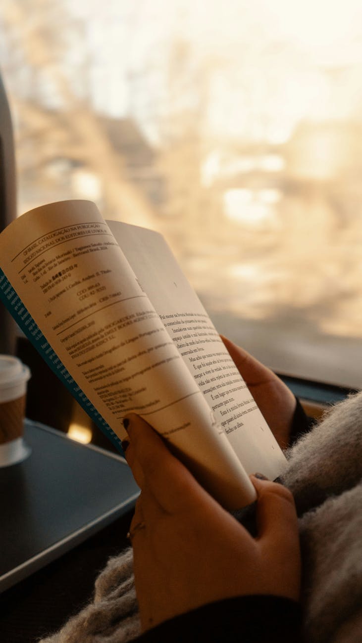 person reading on train with coffee