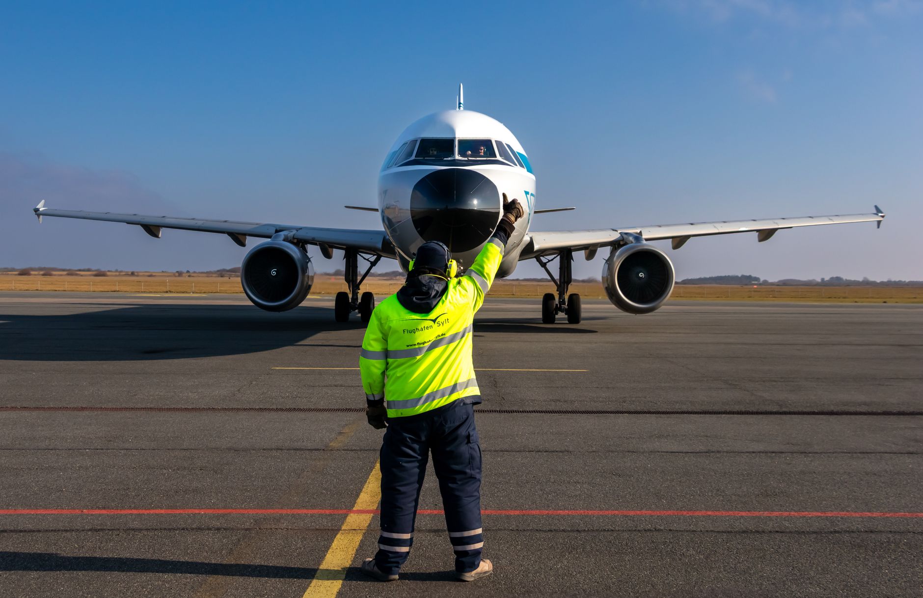 airport worker guiding airplane on runway