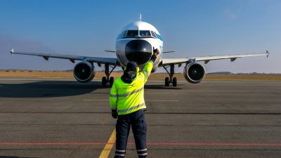 airport worker guiding airplane on runway