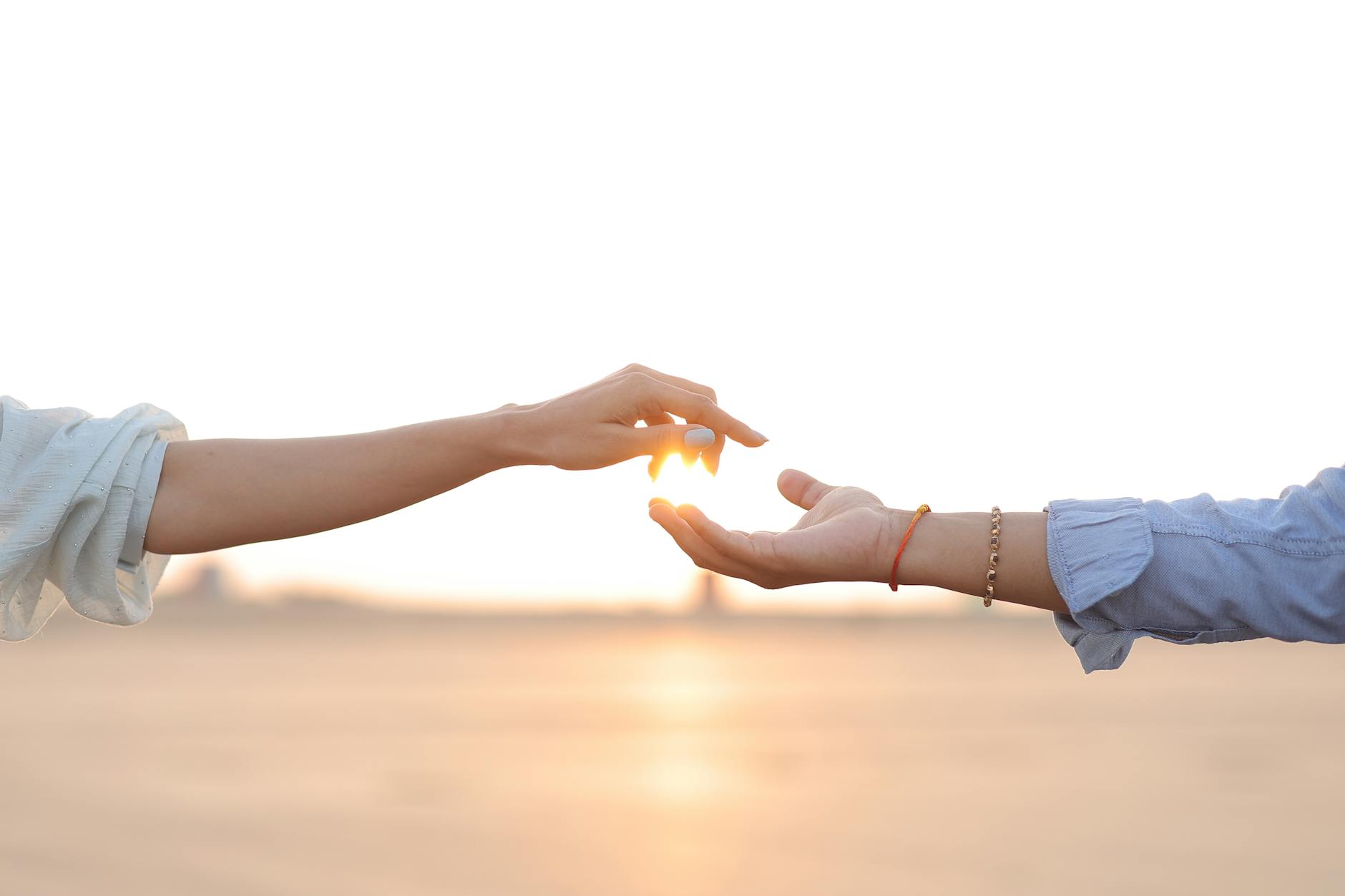 close up of two hands reaching at sunset
