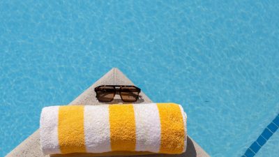 sunny poolside with sunglasses and towel