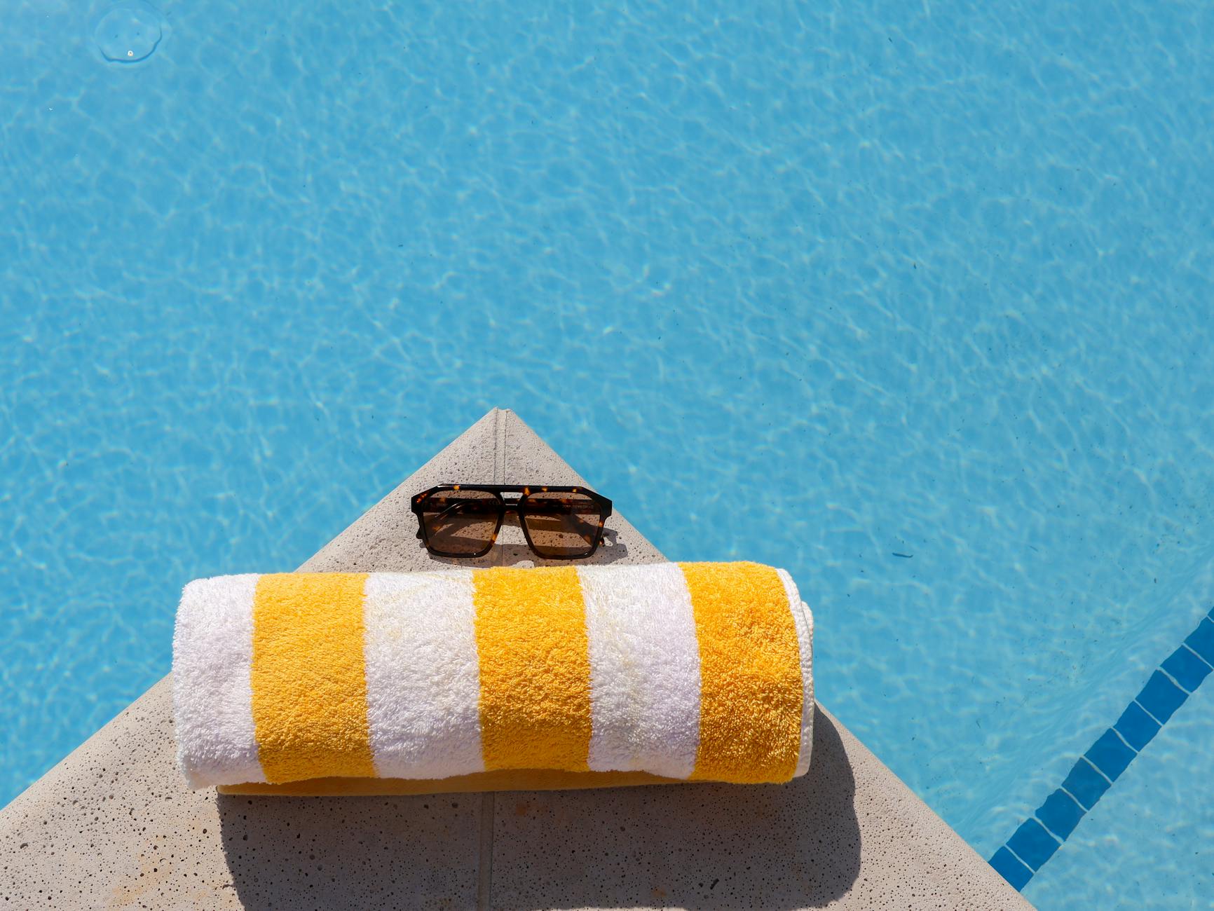 sunny poolside with sunglasses and towel