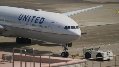 united airline plane being towed on runway