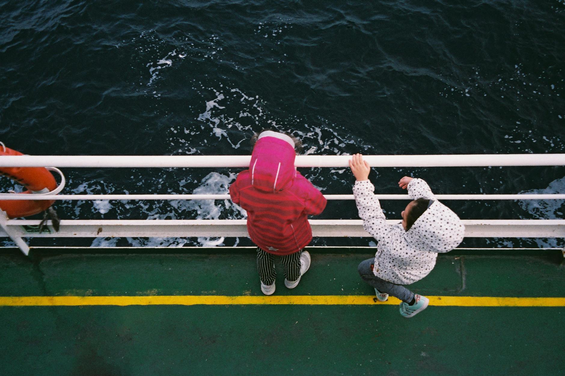 children observing ocean from boat deck