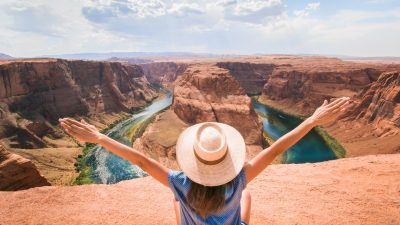 woman sitting on cliff overlooking mountain