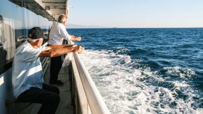 senior men enjoying scenic sea view from ferry