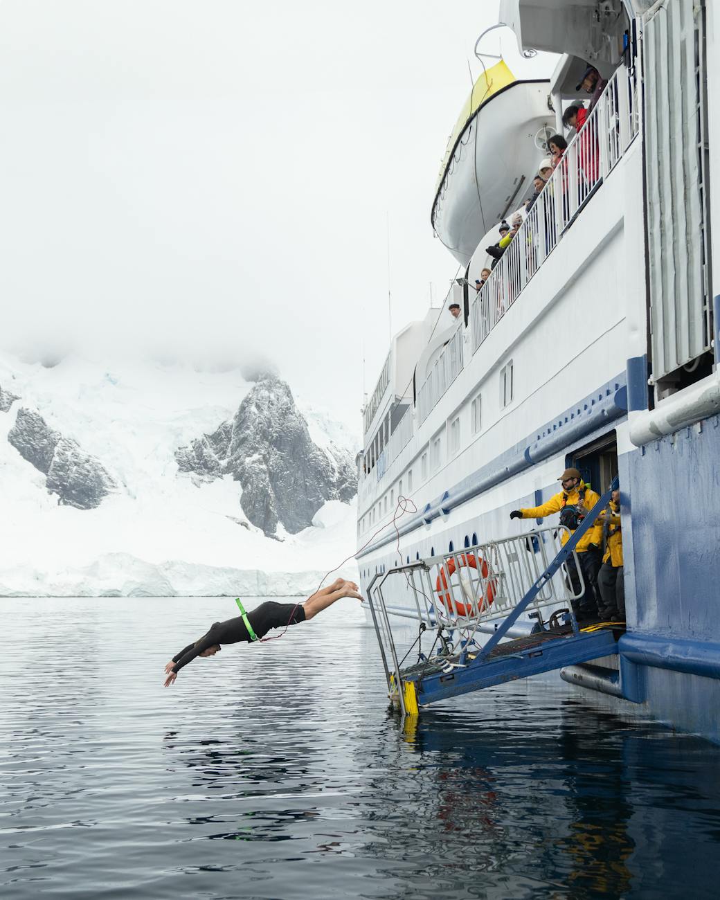 adventurer diving from ship in icy antarctic waters