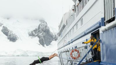adventurer diving from ship in icy antarctic waters