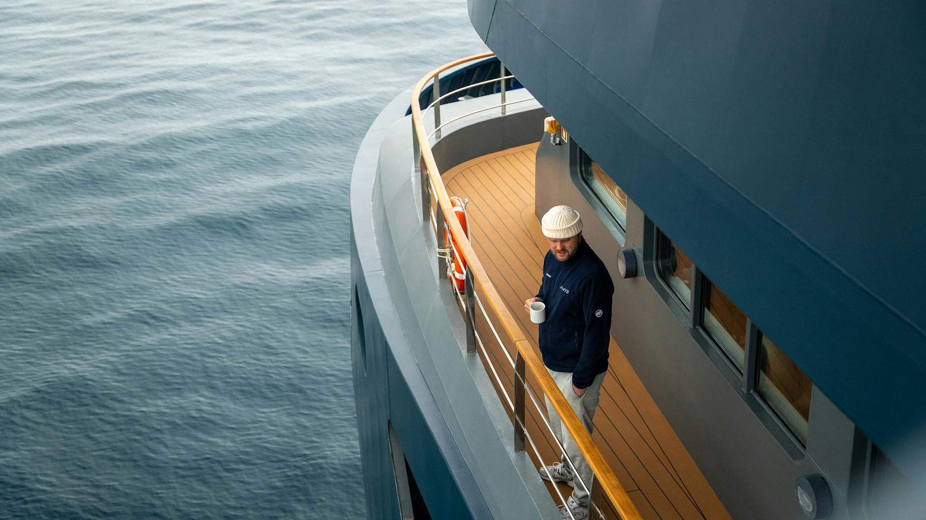 man on yacht deck with coffee at sea