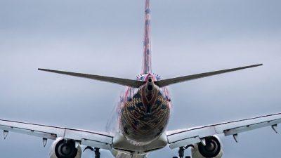 passenger plane landing against cloudy sky