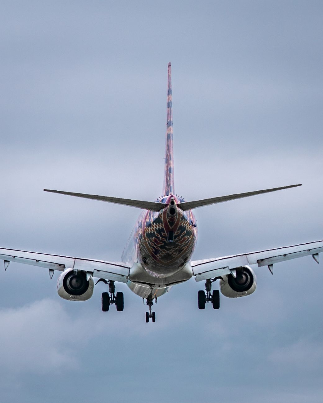 passenger plane landing against cloudy sky
