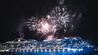 cruise ship illuminated by fireworks at night