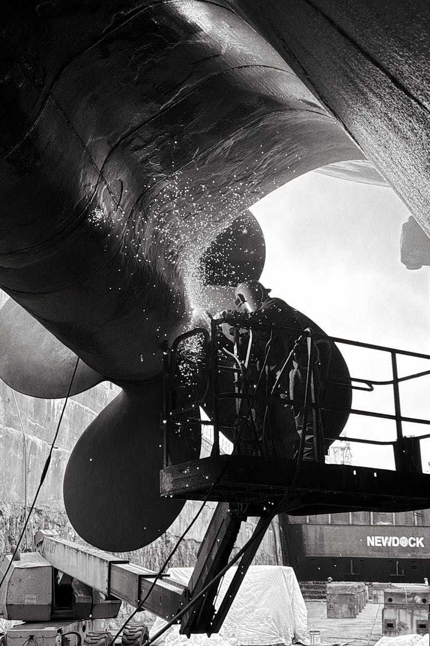 industrial worker welding ship propeller in dry dock