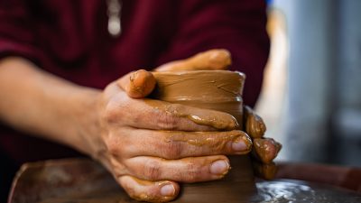 close up of hands molding clay on pottery wheel