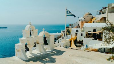 scenic view of fira with greek flag and bells