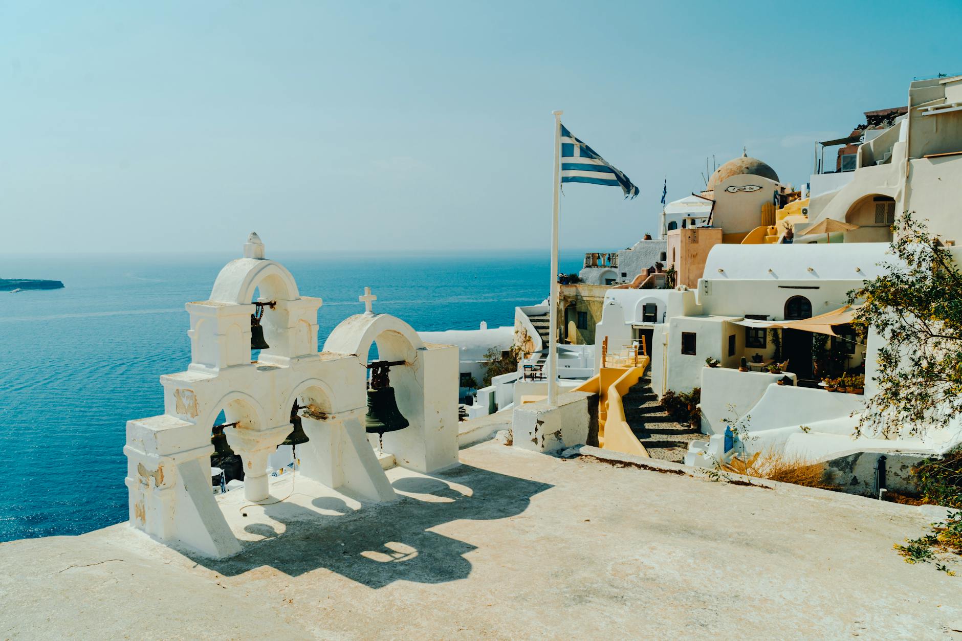 scenic view of fira with greek flag and bells