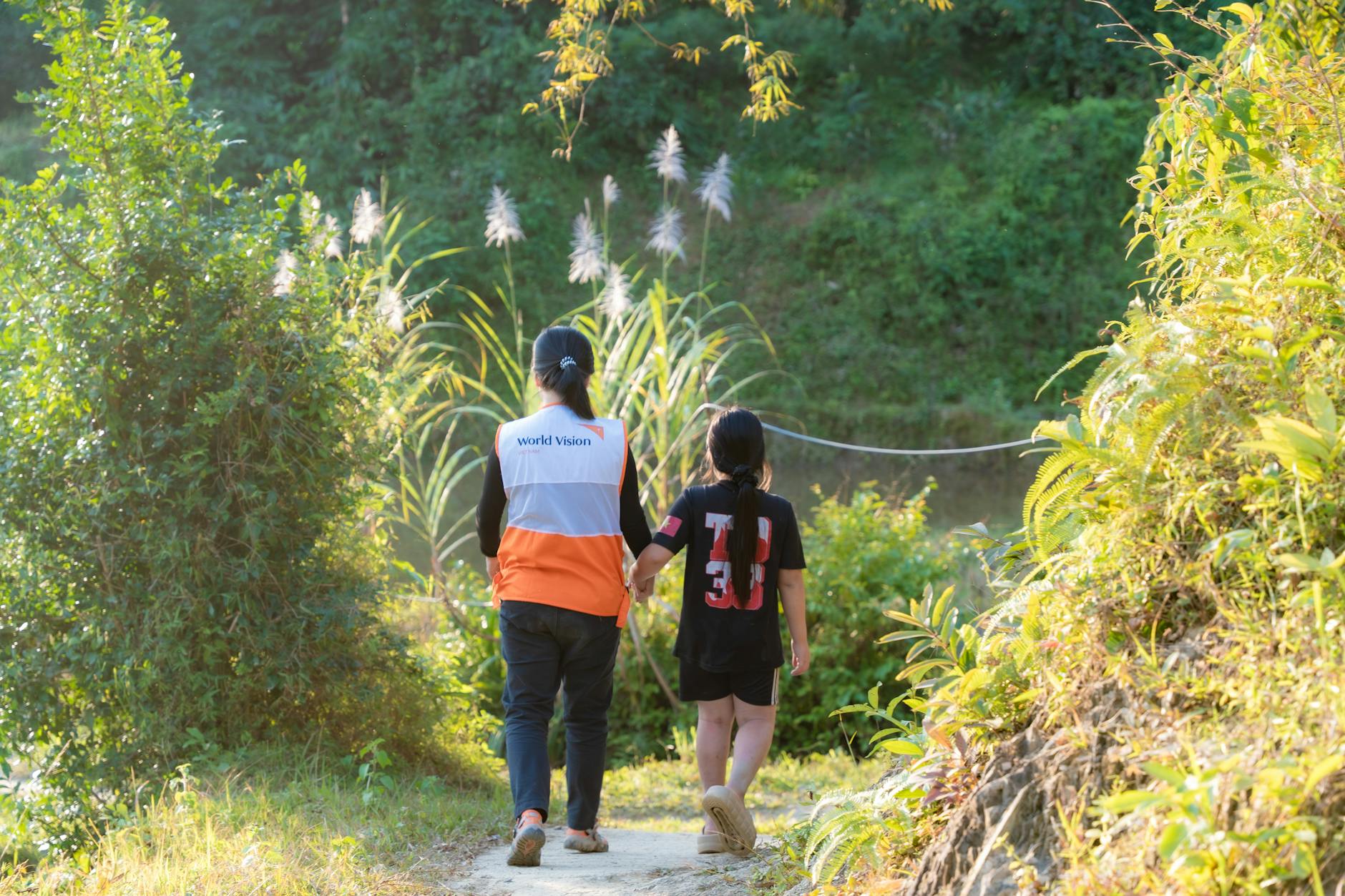 volunteer walking with child in nature path