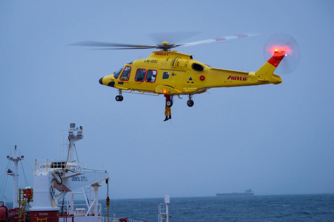 yellow rescue helicopter hovers over vessel at sea