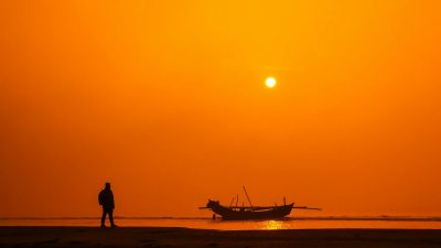 silhouette on beach at sunset with fishing boat