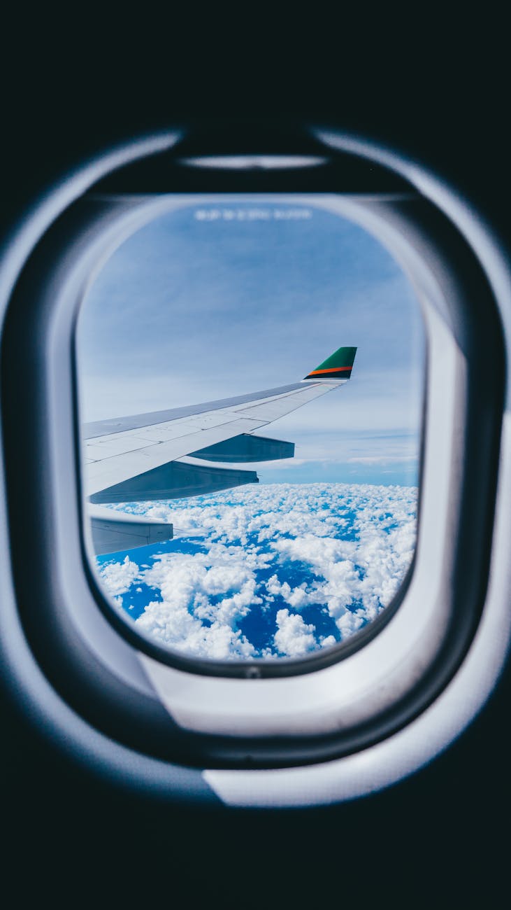 airplane window view of airplane wing and clouds
