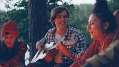 friends enjoying music by campfire outdoors