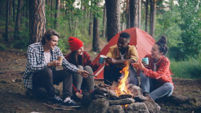 group of friends enjoying campfire in forest