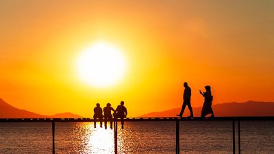 silhouetted people on pier at sunset