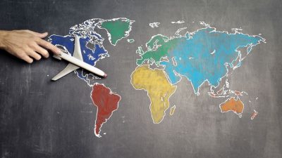 person with toy airplane on world map