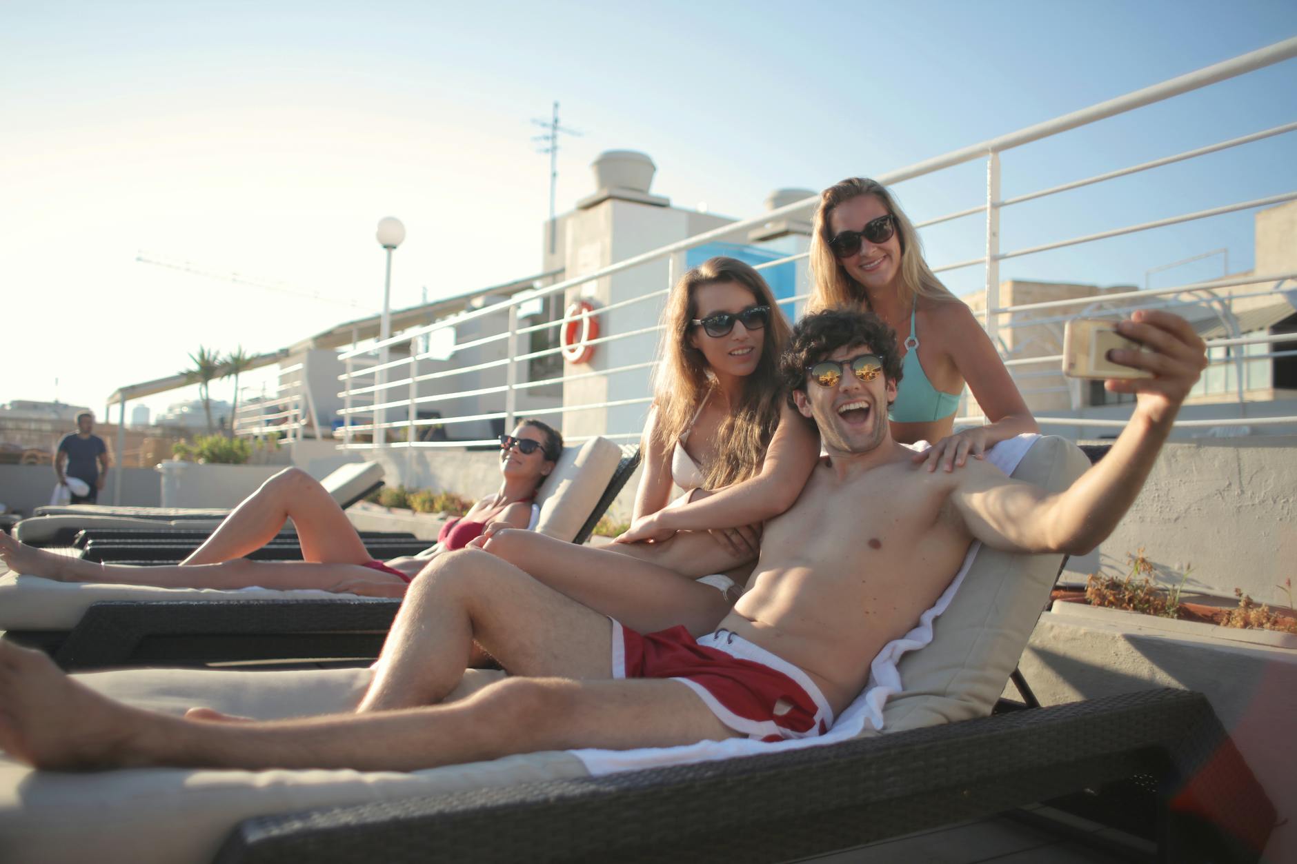 joyful friends spending vacation together on poolside