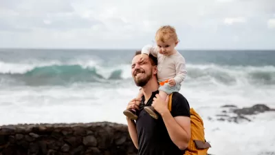 man in black shirt carrying little kid on his shoulder