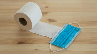 white toilet paper roll and face mask on wooden surface